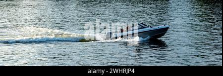 Bateau rapide naviguant dans un fond de mer ondulé bleu. Bateau à moteur blanc avec des éclaboussures de vitesse d'eau et de mousse, vacances d'été en Grèce. Espace. Bannière Banque D'Images