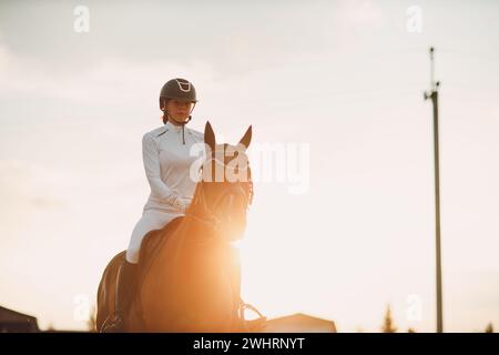 Femme cavalier jockey dans le casque et uniforme blanc préparant les courses de chevaux. Banque D'Images