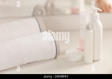 Placez des bouteilles cosmétiques en plastique blanc avec du savon crème et une serviette sur la table blanche à la salle de bain Banque D'Images