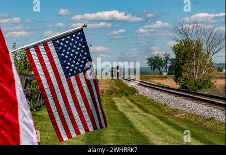 Vue d'un moteur à vapeur approchant, soufflant de la fumée et rangée de drapeaux américains soufflant doucement dans le vent Banque D'Images