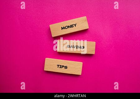 Conseils d'économie d'argent lettrage sur blocs en bois avec fond rose. Symbole commercial conceptuel. Vue de dessus, espace de copie. Banque D'Images