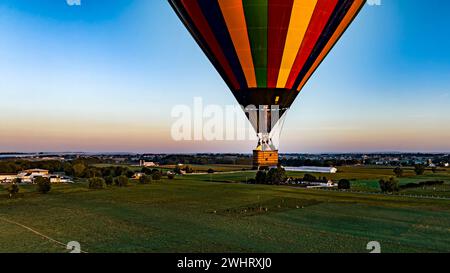 Vue aérienne d'une montgolfière à rayures noires flottant bas au-dessus des champs et des terres agricoles en Amérique rurale Banque D'Images