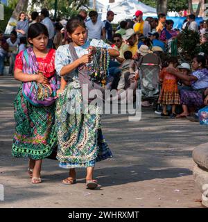 Antigua, Guatemala. Deux jeunes maya femmes en vêtements traditionnels vendre des colliers sur la Plaza de Armas. Santa Semana. Banque D'Images