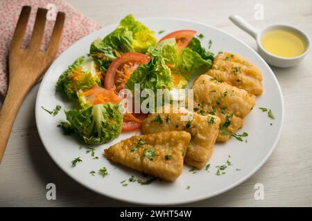 Poisson blanc pané servi avec une salade de tomates. Banque D'Images