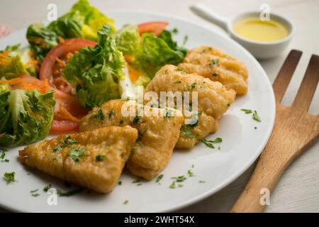 Poisson blanc pané servi avec une salade de tomates. Banque D'Images