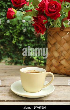 Tasse de café avec un panier de roses en toile de fond Banque D'Images