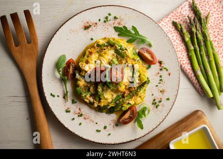Oeufs brouillés avec asperges vertes et tomates cerises. Banque D'Images