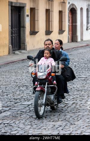 Antigua, Guatemala. Les parents ne font pas de casque avec la petite fille à moto. Banque D'Images