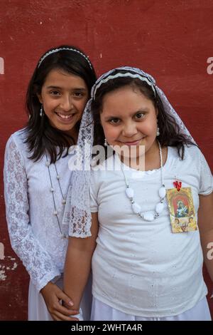 Antigua, Guatemala. Deux jeunes femmes attendant de prendre leur tour portant une Anda. Banque D'Images