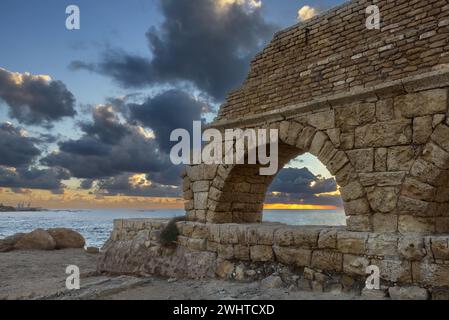 Ancien aqueduc construit par les Romains contre le ciel au coucher du soleil à Césarée Israël Banque D'Images