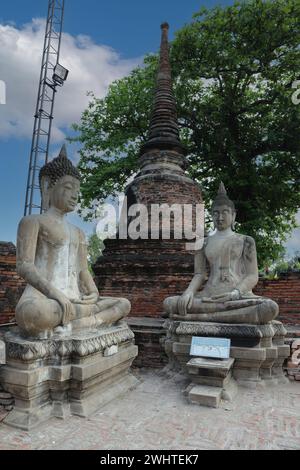 Statues de Bouddhas assis avec une palme vers le haut, à côté d'un petit chedi avec un stupa cloche, au monastère de Wat Yai Chaimongkhon à Ayutthaya, Banque D'Images