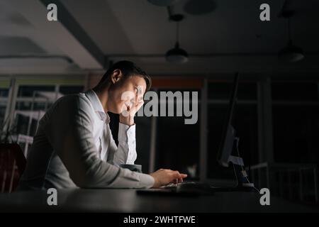 Employé masculin de bureau épuisé ennuyé dans le lieu de travail, regardant l'écran d'ordinateur portable avec le visage apathique indifférent, le travail d'heures supplémentaires. Homme d'affaires fatigué travaillant Banque D'Images