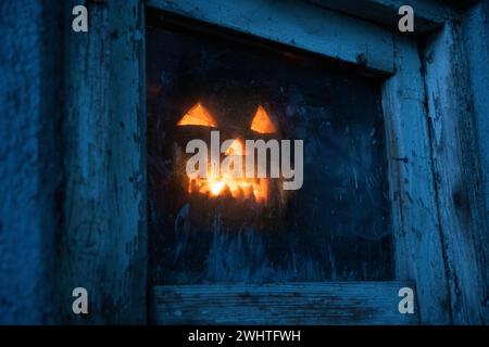 Citrouille d'Halloween effrayante dans la fenêtre la nuit Banque D'Images