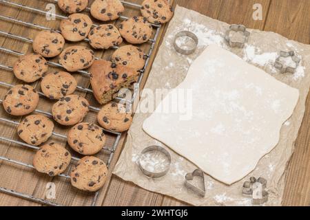 Biscuits prêts à l'emploi. Pâte pour cuire des biscuits sur papier. Moules pour emporte-pièces. Boulangerie de Noël. Fond en bois. Vue de dessus Banque D'Images