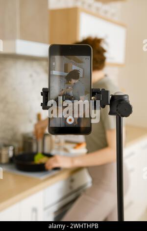 Food vlogger enregistrant la vidéo dans sa cuisine, faisant étape par étape tutoriel d'un reçu Banque D'Images