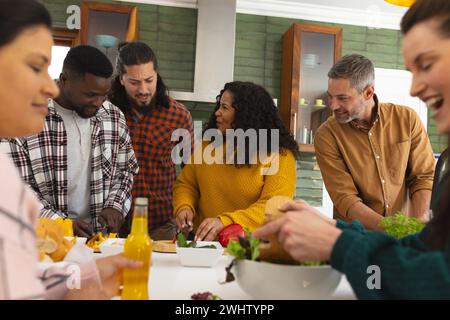 Heureux divers amis masculins et féminins préparant le repas et buvant des boissons dans la cuisine Banque D'Images