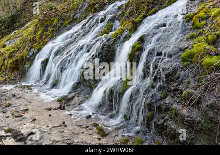 Chute d'eau en cascade au-dessus d'une roche couverte de mousse verte Banque D'Images