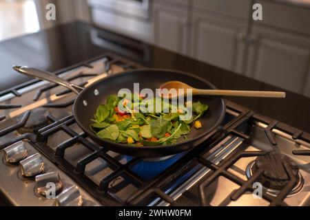 Légumes sautés grésiller dans une poêle sur la cuisinière Banque D'Images