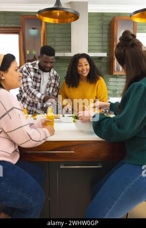 Heureux divers amis masculins et féminins préparant le repas et buvant des boissons dans la cuisine Banque D'Images