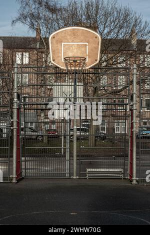 Édimbourg, Écosse, 19 janvier 2024 - panneau de basket-ball avec l'anneau métallique cerceau sur les terrains de basket-ball extérieurs dans le parc avec de vieux bâtiments backgrou Banque D'Images