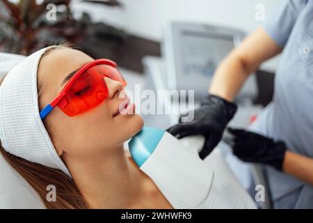 Jeune femme qui reçoit une épilation photo lors d'une visite au centre de beauté dans un salon de beauté Banque D'Images