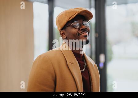 Homme à la mode dans une tenue d'automne élégante souriant à l'intérieur avec une ambiance chaleureuse. Banque D'Images