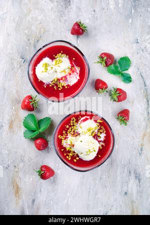 Soupe traditionnelle aux fraises congelée avec glace à la vanille et pistaches écrasées servait de vue de dessus sur un tableau de design avec tex Banque D'Images