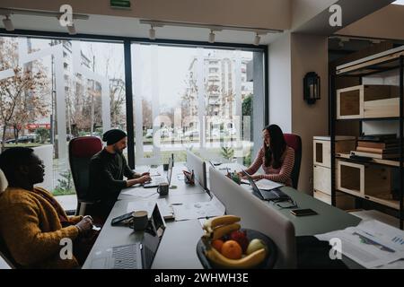 Un groupe multiethnique de professionnels travaillant ensemble dans un environnement de bureau bien éclairé, avec un espace de travail dynamique et collaboratif. Banque D'Images