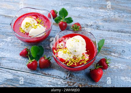 Soupe traditionnelle aux fraises congelée avec glace à la vanille et pistaches écrasées servis en gros plan sur une planche de bois rustique w Banque D'Images