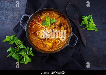 Poulet indien épicé traditionnel curry Madras Rogan Josh avec pilons et riz servis comme vue de dessus dans un bol design nordique Wit Banque D'Images