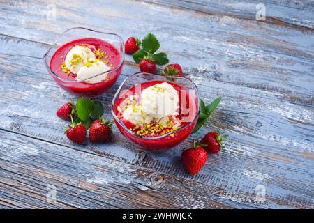 Soupe traditionnelle aux fraises congelée avec glace à la vanille et pistaches écrasées servis en gros plan sur une planche de bois rustique w Banque D'Images