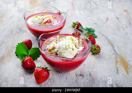 Soupe traditionnelle aux fraises congelée avec glace à la vanille et pistaches écrasées servait de gros plan sur un tableau de design avec tex Banque D'Images