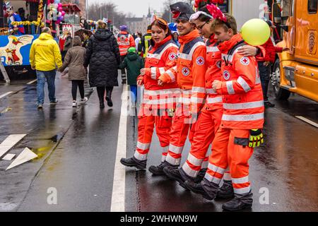 Cottbus, Allemagne. 11 février 2024. Les services d'urgence de la Croix-Rouge allemande sont à Cottbus pour sécuriser la procession des joyeux gens et célébrer avec les participants. Environ 4000 participants présentent 60 camions décorés de la région, Berlin et Saxe à partir de 1,11 heures. Plusieurs milliers de visiteurs regardent le plus grand défilé de carnaval de l'est de l'Allemagne depuis le bord de la route. Crédit : Frank Hammerschmidt/dpa/Alamy Live News Banque D'Images