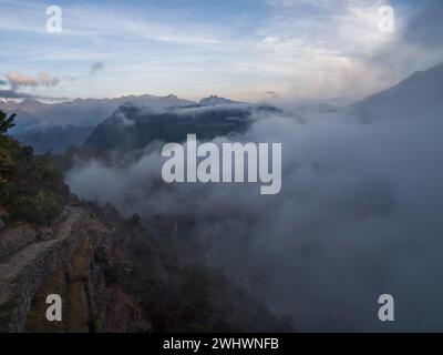 Fin du trek Inca Trail au lever du soleil avec la ville sacrée de Machu Picchu sous la couverture de nuages entre les montagnes, Urubamba, Cuzco, Pérou Banque D'Images