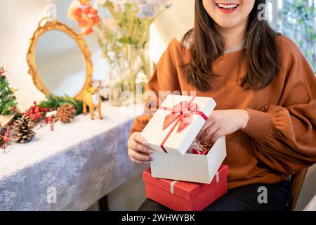 Heureuse femme asiatique ouvre boîte de Noël et surprises. préparation de surprise pour noël présent en vacances Banque D'Images