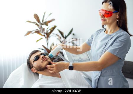 Jeune homme recevant l'épilation photo tout en visitant le centre de beauté sur le salon Banque D'Images