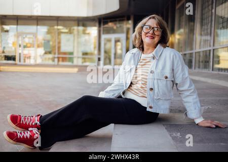 Femme senior en vêtements décontractés rit et regarde dans la caméra Banque D'Images