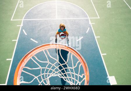 Vue en angle depuis le dessus de l'enfant jouant au basket-ball sur le terrain de jeu. Banque D'Images