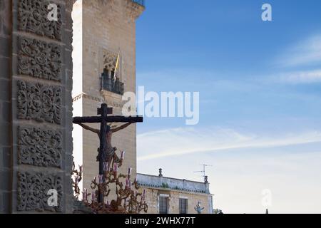 Image capturée pendant la semaine Sainte à Jerez de la Frontera, Espagne, montrant une croix ornée devant la cathédrale sous un ciel bleu clair. Banque D'Images