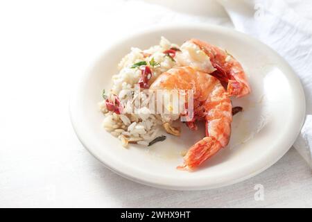 Crevettes tigrées frites ou crevettes et riz épicé avec de l'ail, du piment rouge et des herbes sur une assiette blanche et un fond clair, h. Banque D'Images