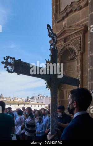 Jerez de la Frontera, Espagne - 11 février 2024 : procession religieuse dans la semaine sainte, montrant une croix ornée, des fidèles et l'architecture historique Banque D'Images