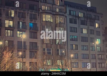 Bruxelles, Belgique. 5 février 2024. Façade de bâtiments à Bruxelles. Photographie de rue. Immeuble à plusieurs étages (appartements) avec lumières allumées Banque D'Images