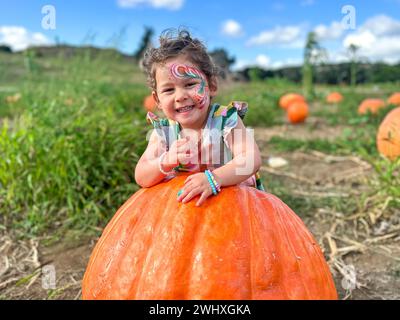 Petite fille cueillant des citrouilles sur le patch de citrouille d'Halloween. Enfant jouant dans un champ de squash. Banque D'Images