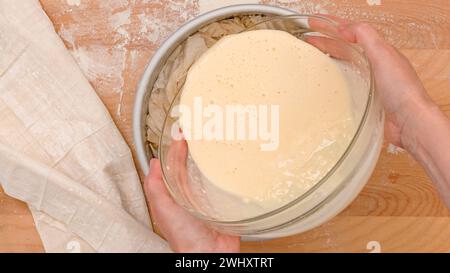 Chef versant la garniture crémeuse dans un moule de cuisson, processus de cuisson en gros plan Banque D'Images