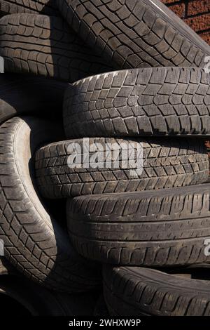 Pile de pneus en caoutchouc de véhicules automobiles jetés dans une cour de recyclage. Banque D'Images