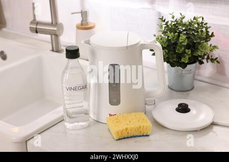 Nettoyage de la bouilloire électrique. Bouteille de vinaigre et éponge sur le comptoir dans la cuisine Banque D'Images