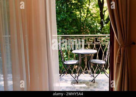 Vue de la fenêtre à la terrasse avec une table et des chaises sur elle Banque D'Images