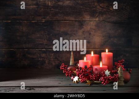 Quatrième avènement avec des bougies rouges allumées dans une couronne de baies de décoration, boules de Noël et biscuits étoilés à la cannelle contre un da Banque D'Images