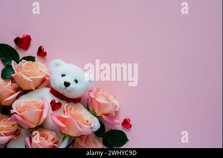 Poupée d'ours en peluche blanche avec des roses roses et forme d'amour sur fond rose pour le concept de Saint-Valentin. Banque D'Images