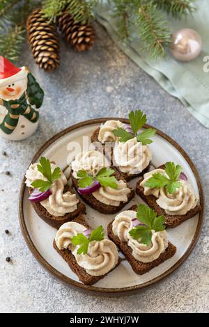 Hors-d'œuvre créatif noël. Pâté crémeux sandwichs de hareng sur un pain de seigle sur la table de fête. Copier l'espace. Banque D'Images